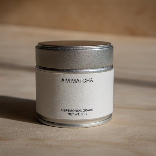 AM.MATCHA ceremonial grade matcha container on a wooden surface